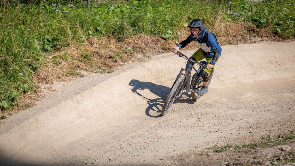 Cyclist riding through a berm on a dusty bike park trail