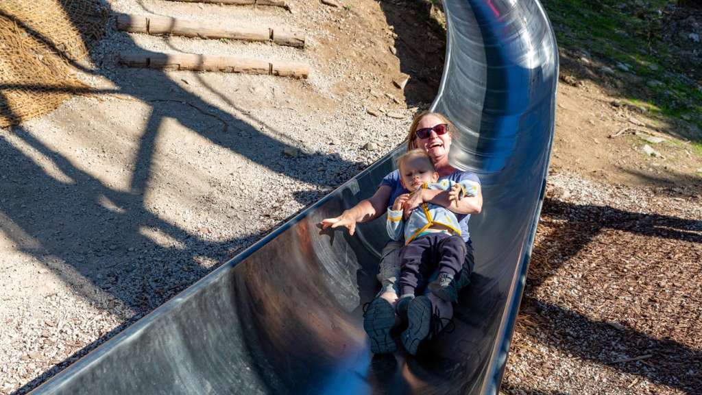 Smiling grandmother after riding a stainless-steel slide with her grandson